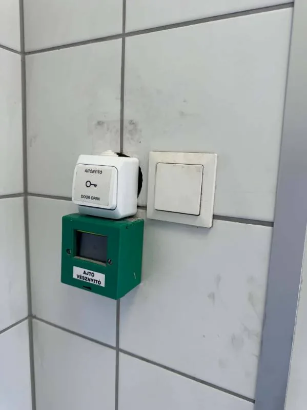 Ajtónyitó gomb és vészkijárat-nyitó csempézett falon